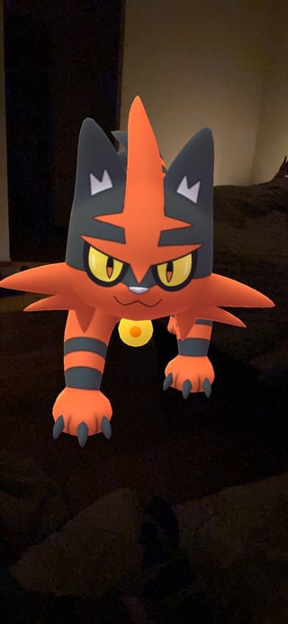 Orange and black spiky cat-like Pokémon figure with yellow eyes and a yellow belly marking, displayed indoors